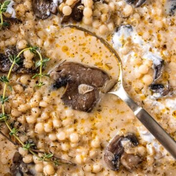 Close up of Creamy Mushroom and Pearl Couscous Soup with sour cream and fresh herbs.