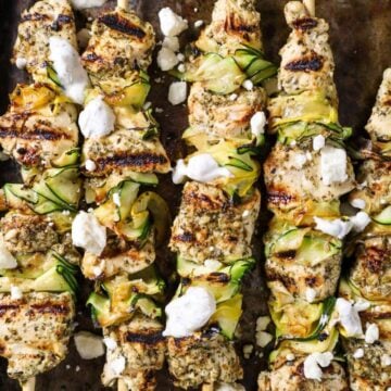 Grilled Chicken and zucchini Skewers with Tzatziki and Feta on a sheet pan.