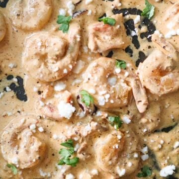 Closeup of creamy chipotle shrimp with queso fresco and cilantro.