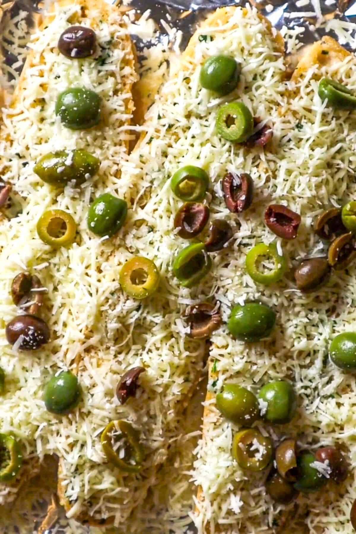 french bread covered in cheese and sliced olives